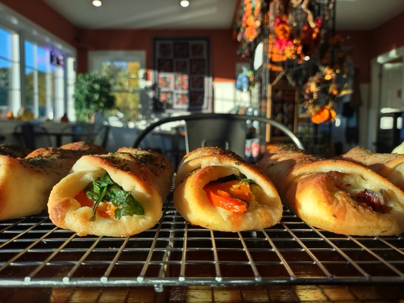 Golden baked rolls filled with spinach and roasted peppers, cooling on a wire rack