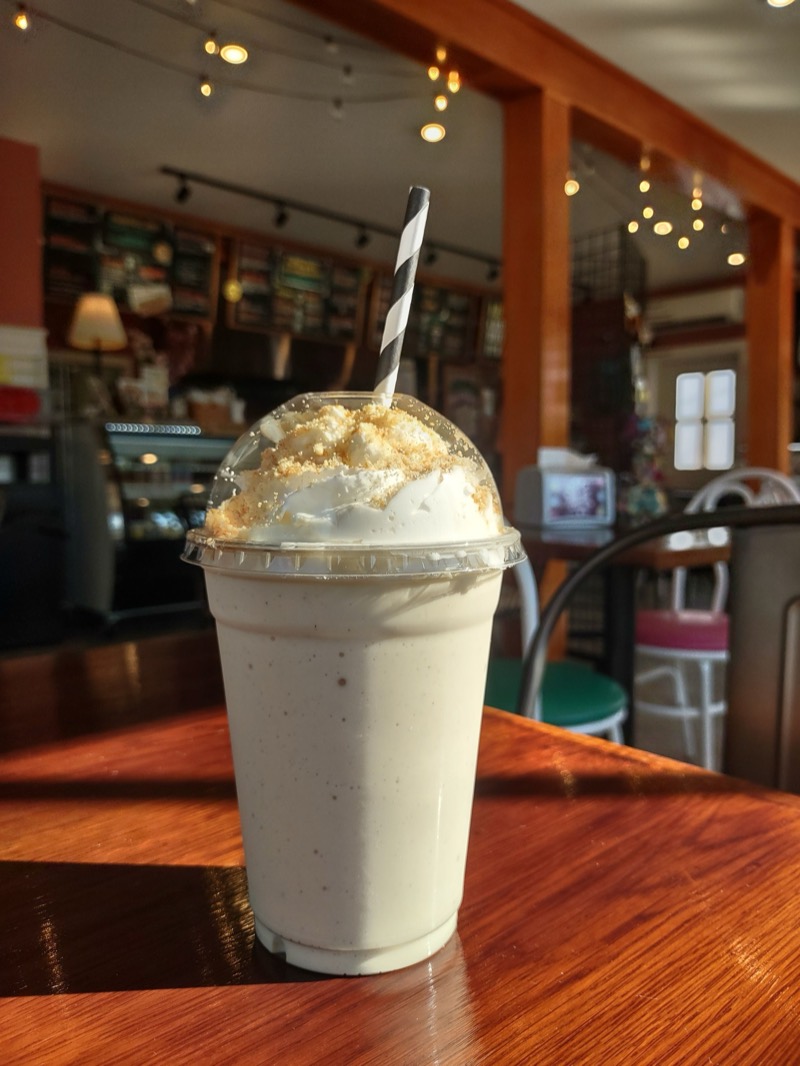 A frozen chai latte topped with whipped cream and cinnamon, inside the cafe