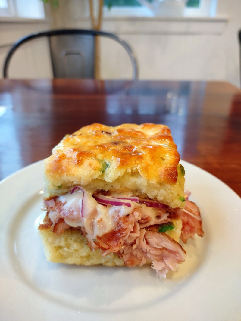 A bacon jalapeño biscuit sandwich with seared ham, Swiss cheese, red onion and sauce