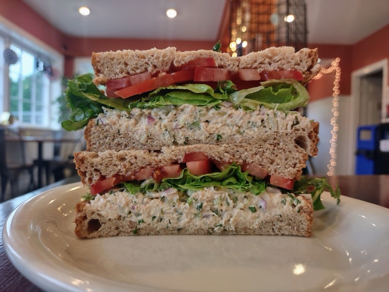 A tuna salad sandwich on wheat bread with lettuce and tomato